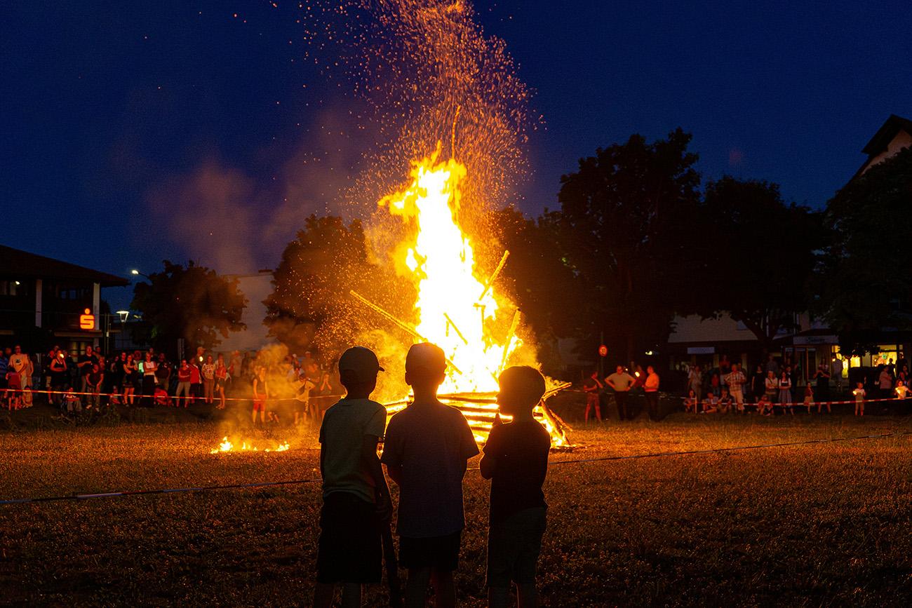 Three children stood around a glowing bonfire